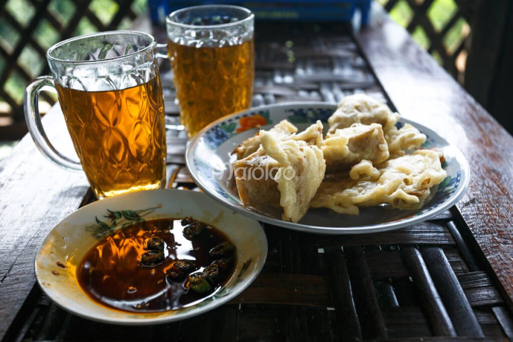 A plate of fried snacks with dipping sauce and two glasses of tea at a café near Nglinggo Tea Plantation.