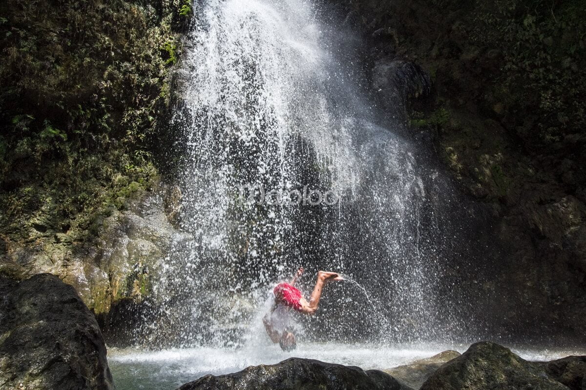 A person performing a flip in one of the natural pools at Sri Gethuk Waterfall in Yogyakarta, Indonesia.