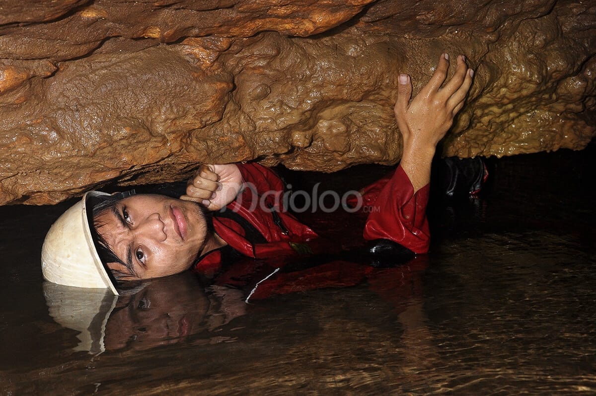 Explorer navigating a tight, water-filled passage in Cerme Cave.