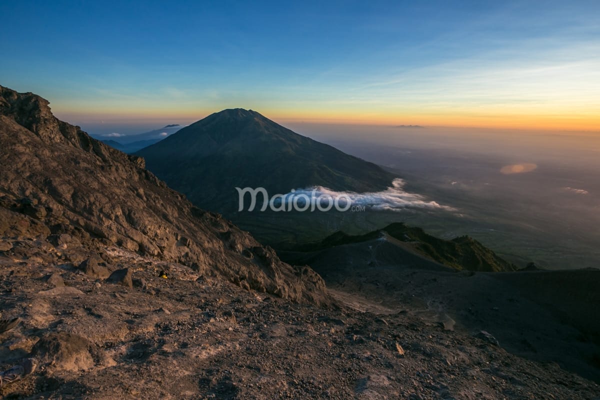 View of Pasar Bubrah, the rocky expanse at the base of Mount Merapi’s summit, with surrounding mountains and valleys during sunrise.