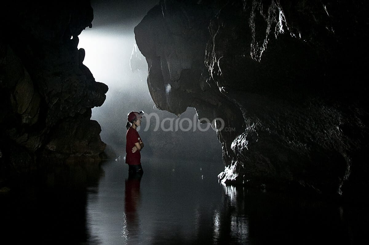 Explorer standing in a partially illuminated entrance of Cerme Cave.