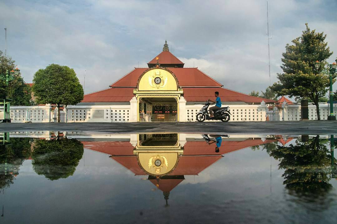 Gedhe Keraton Yogyakarta Mosque in Yogyakarta with its reflection in a water puddle.