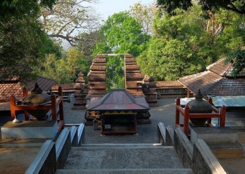 Stone staircase leading to the Imogiri Royal Cemetery, with traditional Javanese-style brick gateways surrounded by lush trees.