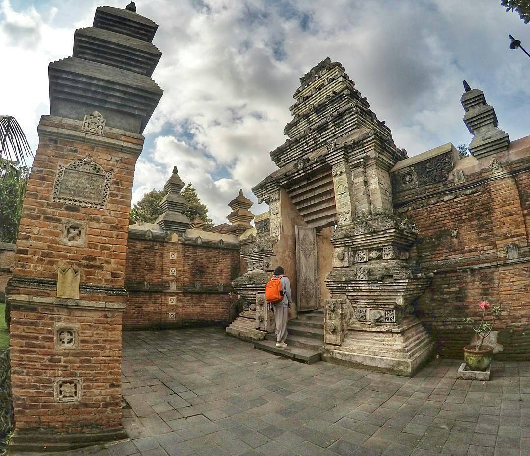 A visitor walking into the ancient entrance of Kotagede's royal tomb complex, surrounded by red brick Hindu-Javanese architecture.